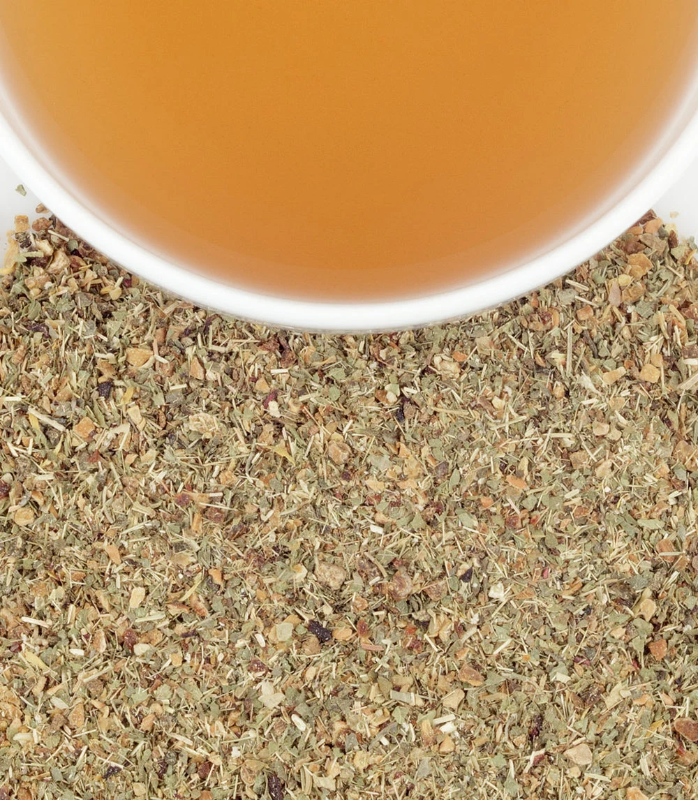 A white cup of Harney & Sons Lemon Herbal above a bed of dried herbal ingredients