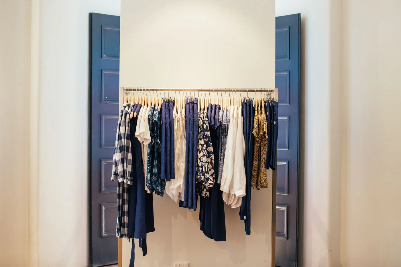 Clothing on hangers inside a blue wardrobe