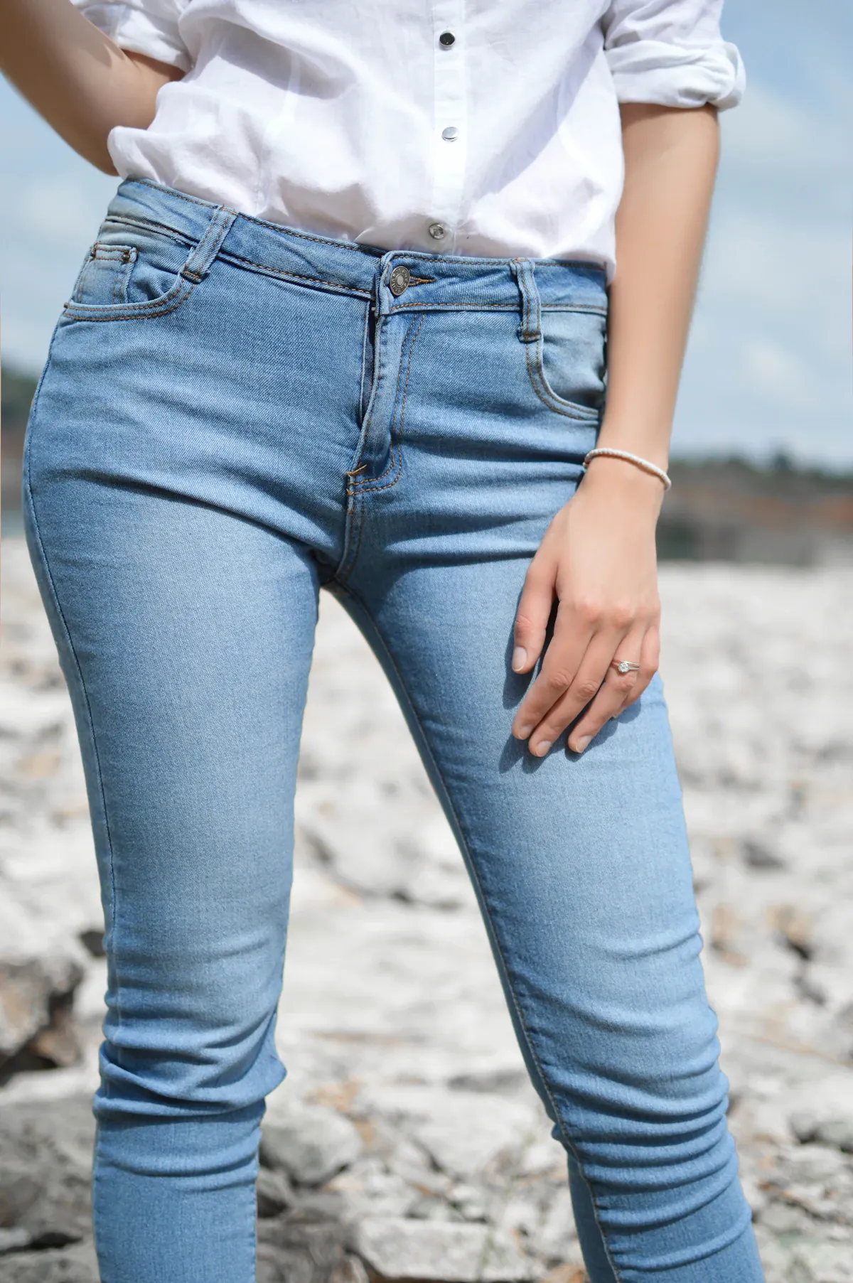 Close view of a white button-front shirt tucked into blue jeans