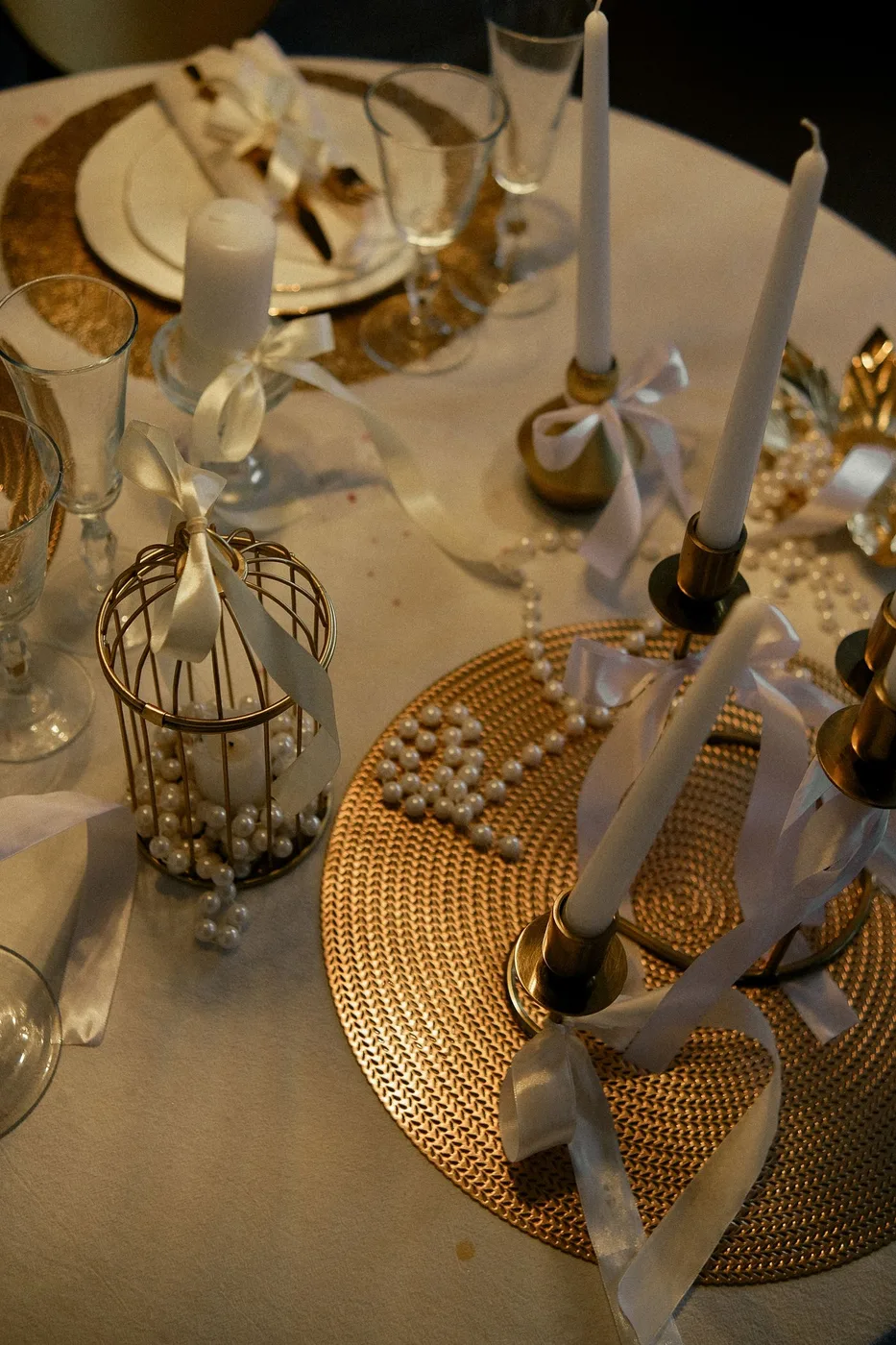 Pale candles, ribbons, glassware and decorative objects on a table