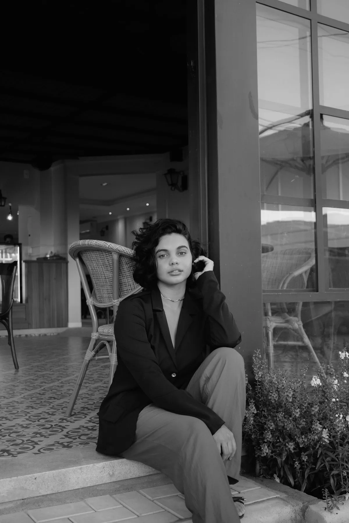 Black-and-white photograph of a woman in a blazer seated at a cafe