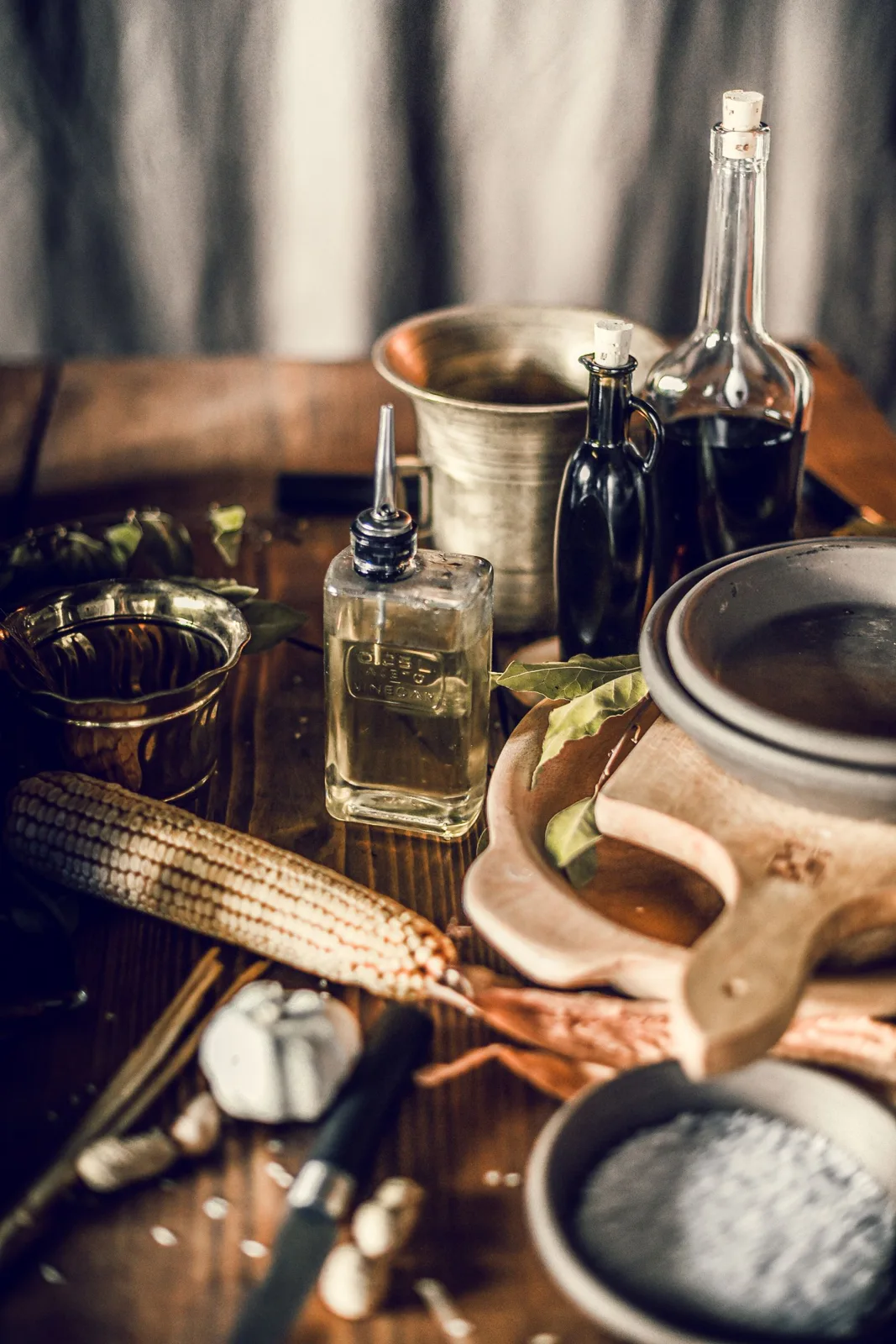 Bottles and a lidded ceramic container on a wooden kitchen surface