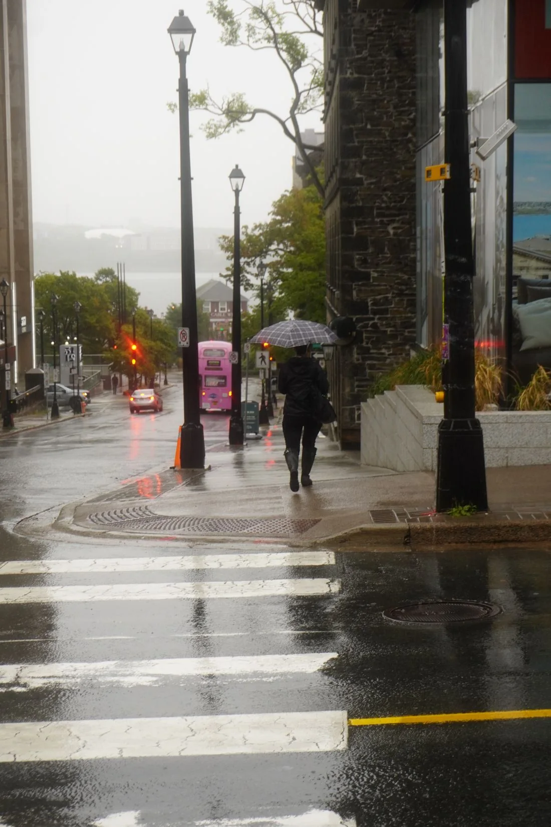 Person with an umbrella walking on a rainy city street